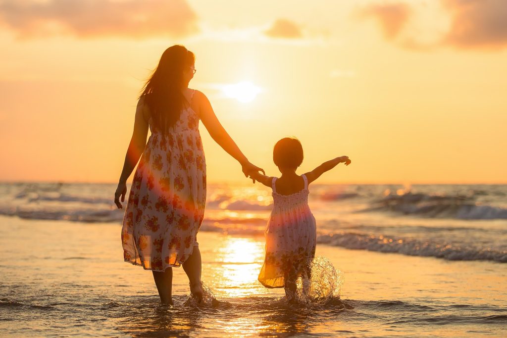 Mother and child walking together at the beach representing ongoing family healthcare support
